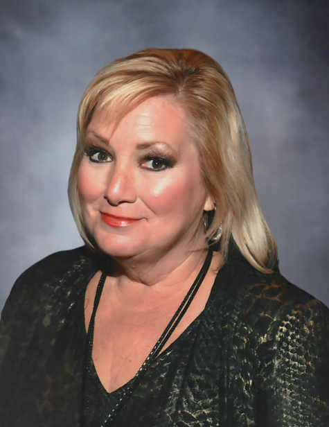 Smiling woman in dark patterned blouse.
