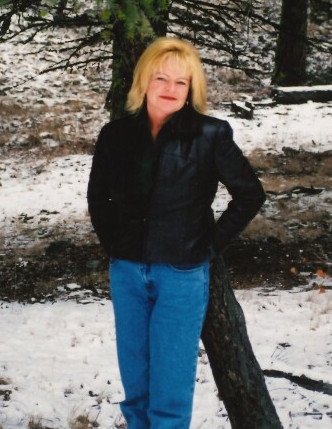 Person in leather jacket standing by snowy tree