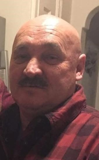 Man in red checkered shirt indoors.