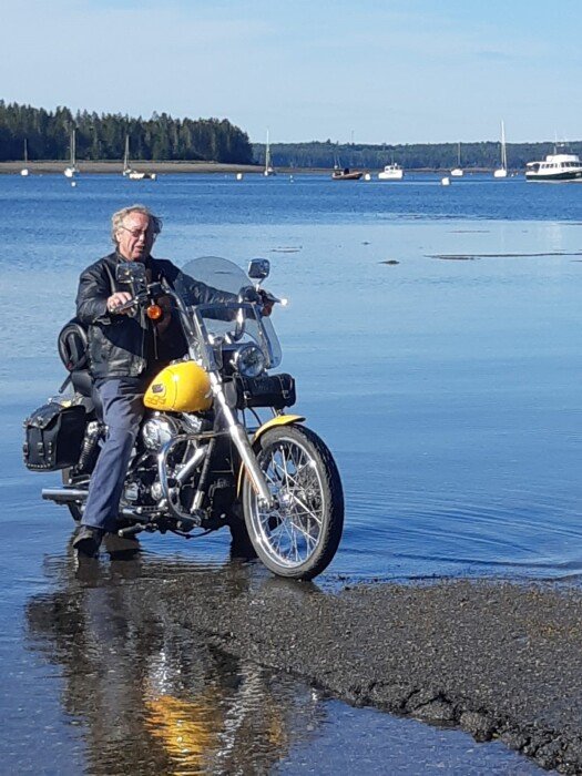 HUNTINGTON, Murray Huntington Rider on yellow motorcycle near the water