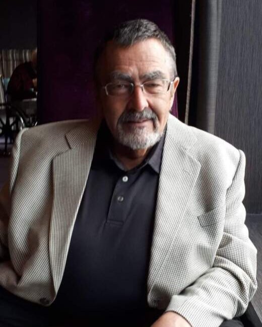 Man in blazer sitting indoors.
