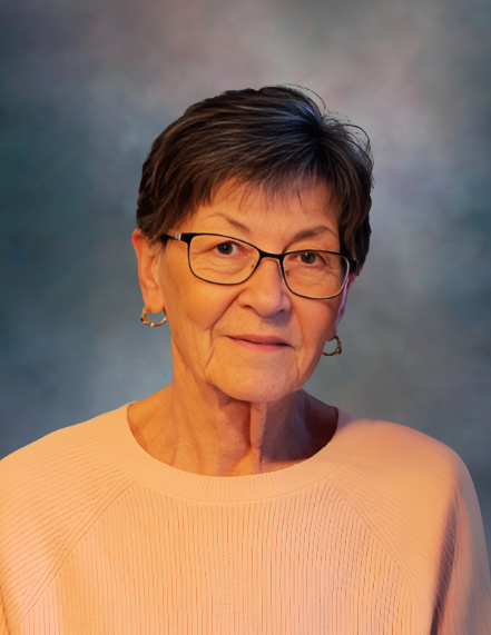 Elderly woman with glasses and short hair smiling.