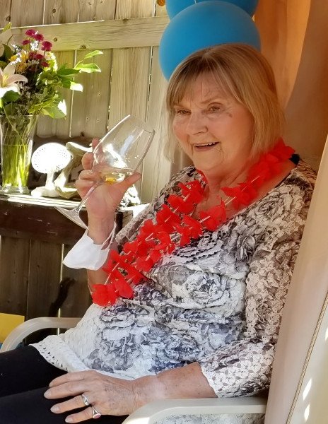 Smiling woman with wine glass and red lei