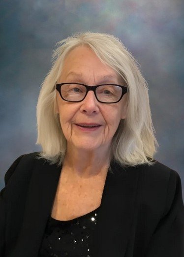 Smiling elderly woman with glasses and white hair.