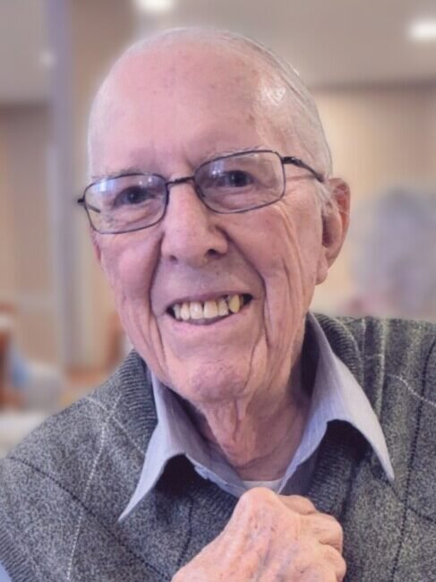 Smiling elderly man wearing glasses indoors.