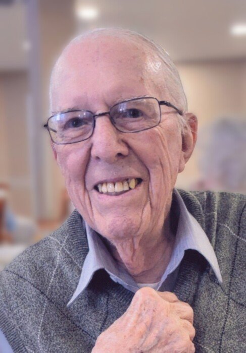 Smiling elderly man wearing glasses indoors.