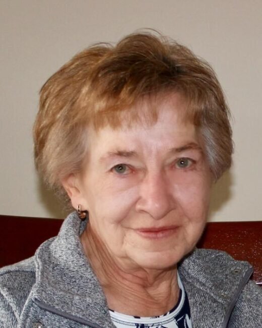 Portrait of an elderly woman smiling indoors.