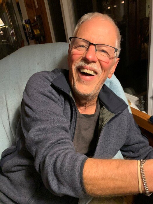 TRIMBLE, Robert Trimble Smiling elderly person in casual attire indoors.