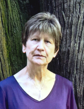 Woman standing in front of tree trunk.