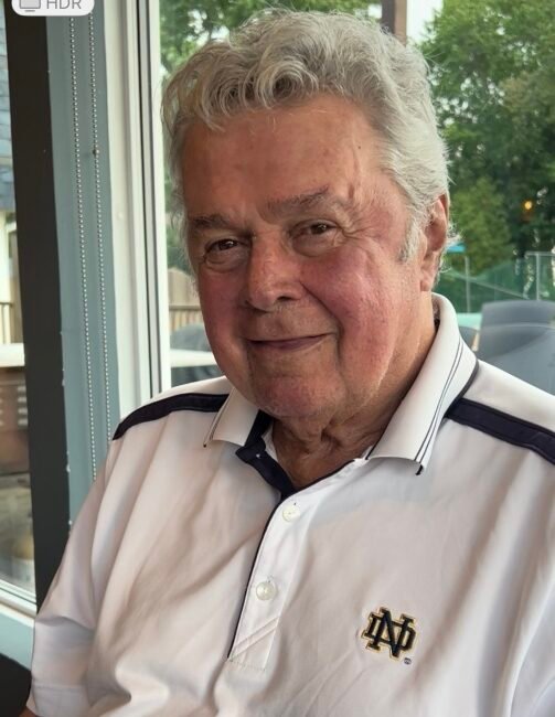 Elderly man in white polo shirt by window.