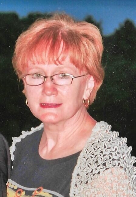 Person with glasses outside, wearing a lace shirt.