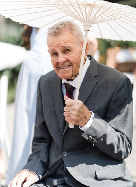 Elderly man in suit holding a white parasol.