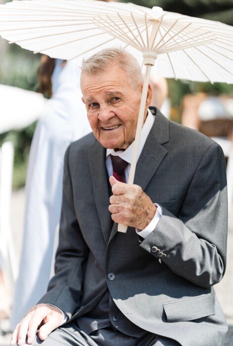 Elderly man in suit holding a white parasol.