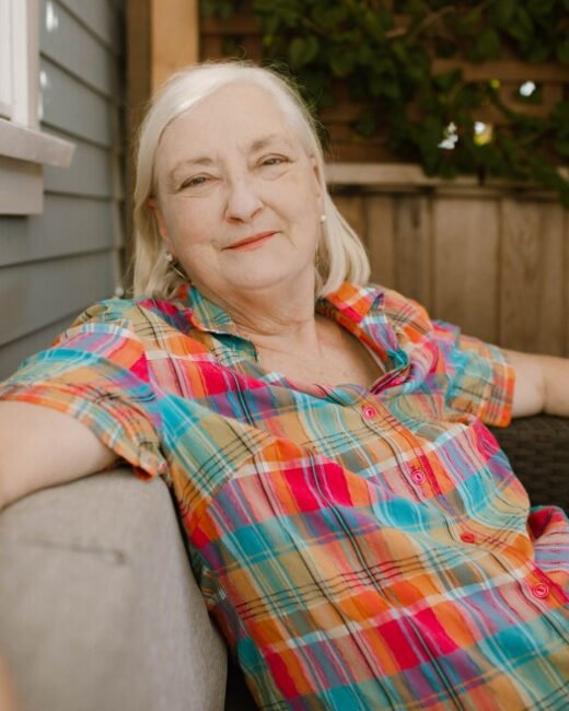 Smiling woman in colorful plaid shirt on porch