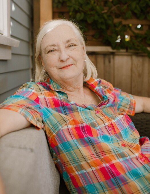 Smiling woman in colorful plaid shirt on porch