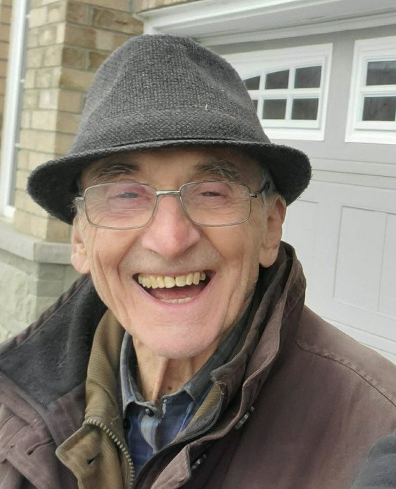 BURKE, Eric Burke Smiling elderly man wearing glasses and hat outside.