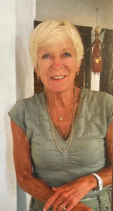 Smiling woman with short blonde hair inside home.