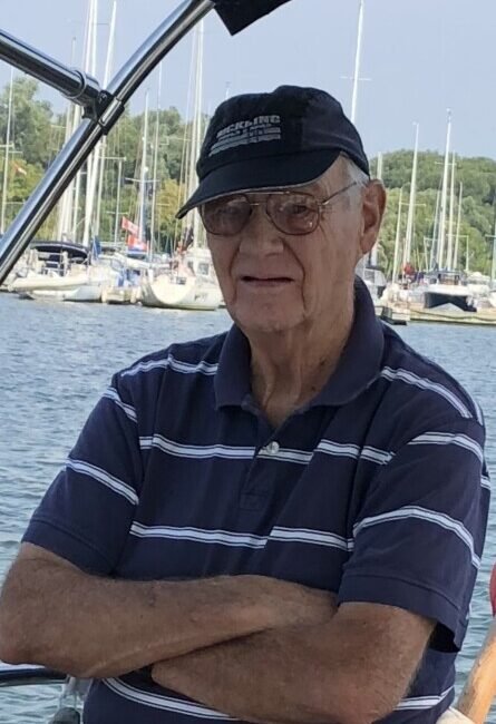Older man on a boat with marina background.