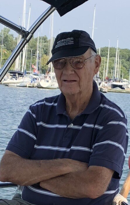 Older man on a boat with marina background.