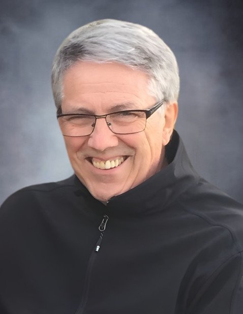 Smiling person with glasses and gray hair