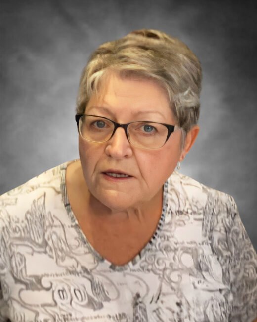 Elderly woman wearing glasses, looking forward.