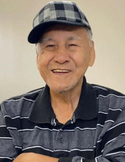 Smiling man wearing plaid cap and striped shirt.