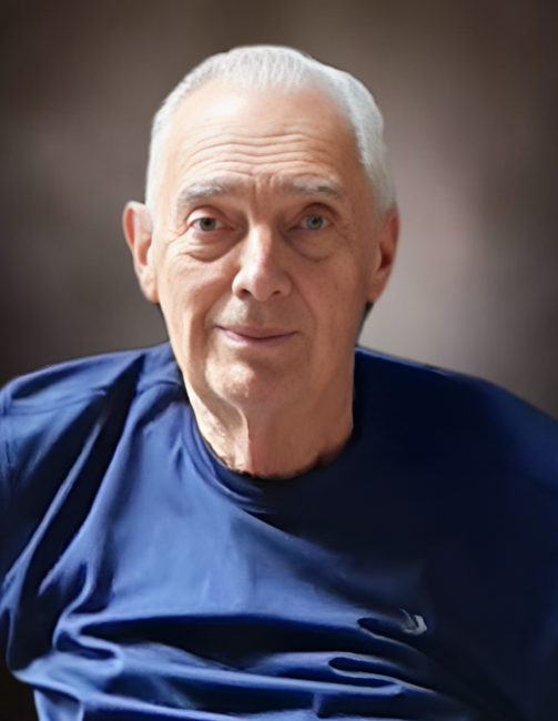Elderly man in blue shirt smiling.