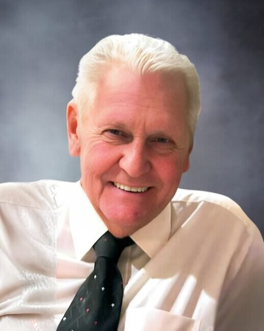 Smiling man in white shirt with black tie.
