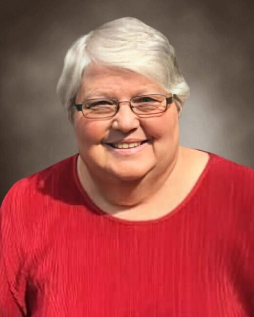 Person smiling in red sweater with glasses.