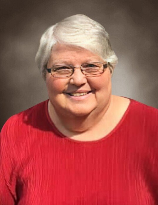 Person smiling in red sweater with glasses.