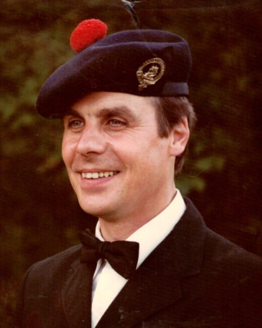 Man wearing Scottish hat and suit, smiling outdoors.