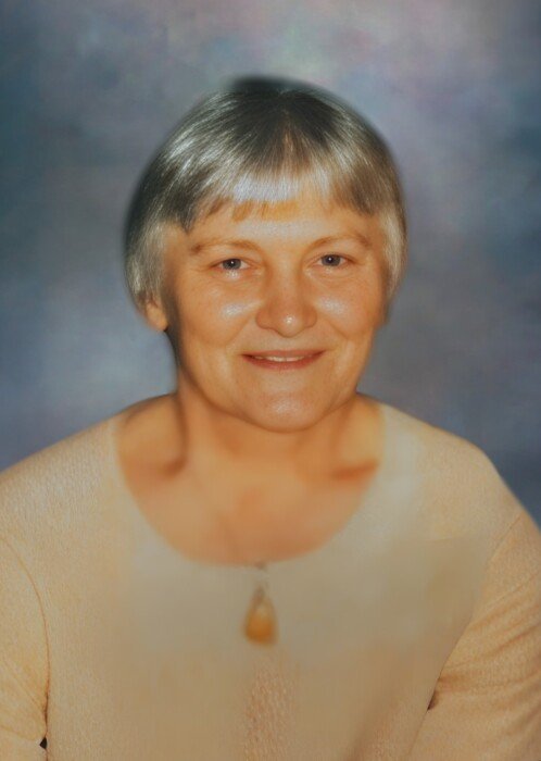 Smiling woman with short hair and neutral background.