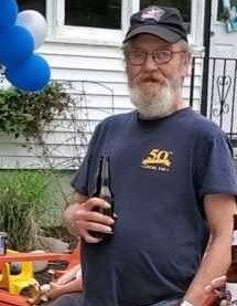 Man holds beer bottles at outdoor gathering.