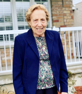 Smiling elderly woman in blue jacket outside home