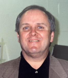 Smiling man in a suit jacket and shirt.