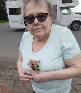 Elderly woman holding flowers near RV