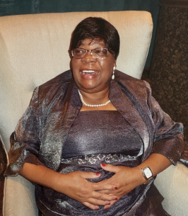 Smiling woman seated in elegant attire.