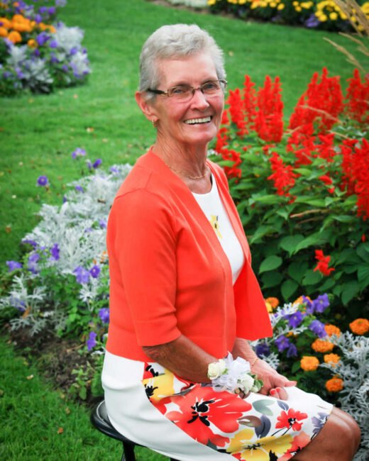 Smiling woman seated in colorful flower garden.