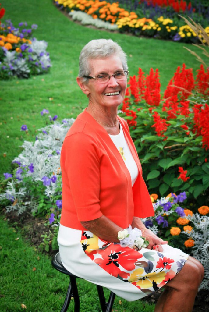 Smiling woman seated in colorful flower garden.