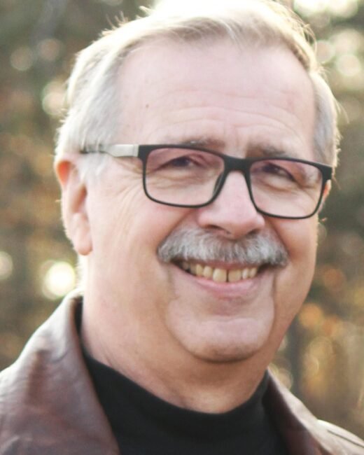 Smiling gray-haired man with glasses outdoors