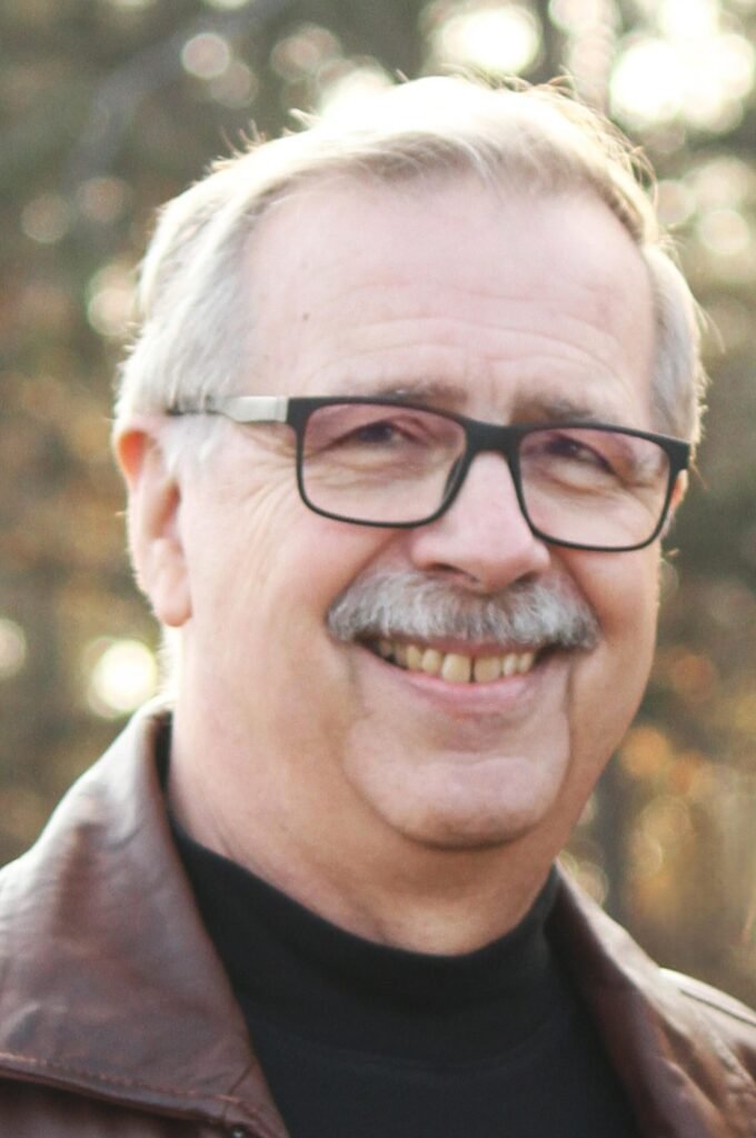Smiling gray-haired man with glasses outdoors