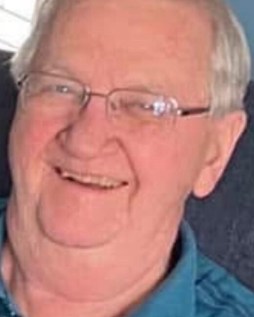 Smiling person in blue shirt with glasses.