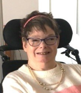 MILNER, Charlene Frances Milner Woman smiling in wheelchair with pearl necklace.