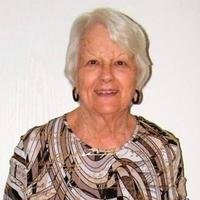 Smiling elderly woman in patterned blouse.
