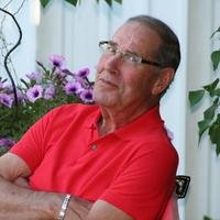 Man in red shirt sitting by flowers.