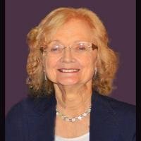 Smiling elderly woman with glasses and curly hair.