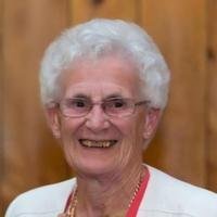 Smiling elderly woman with glasses and white hair.