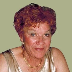 Older woman smiling, wearing gold dress and earrings.