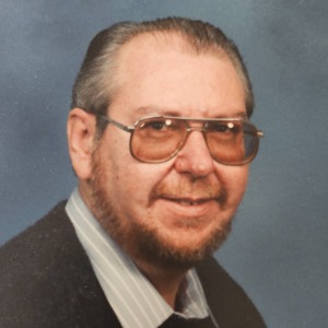 Elderly man with glasses and a beard smiling
