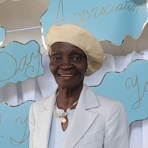 Smiling person in light clothing and beret.